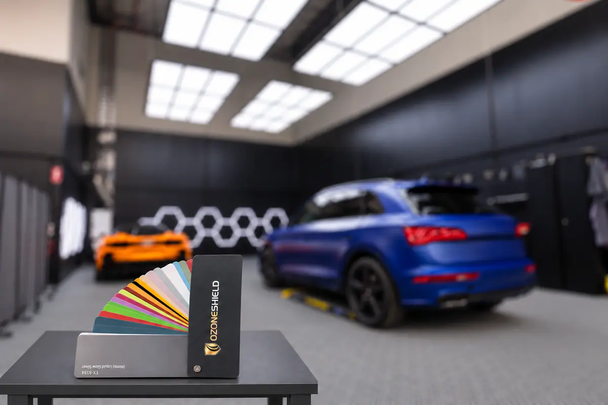 OzoneShield swatch book in the studio with a wrapped blue Audi and an orange McLaren